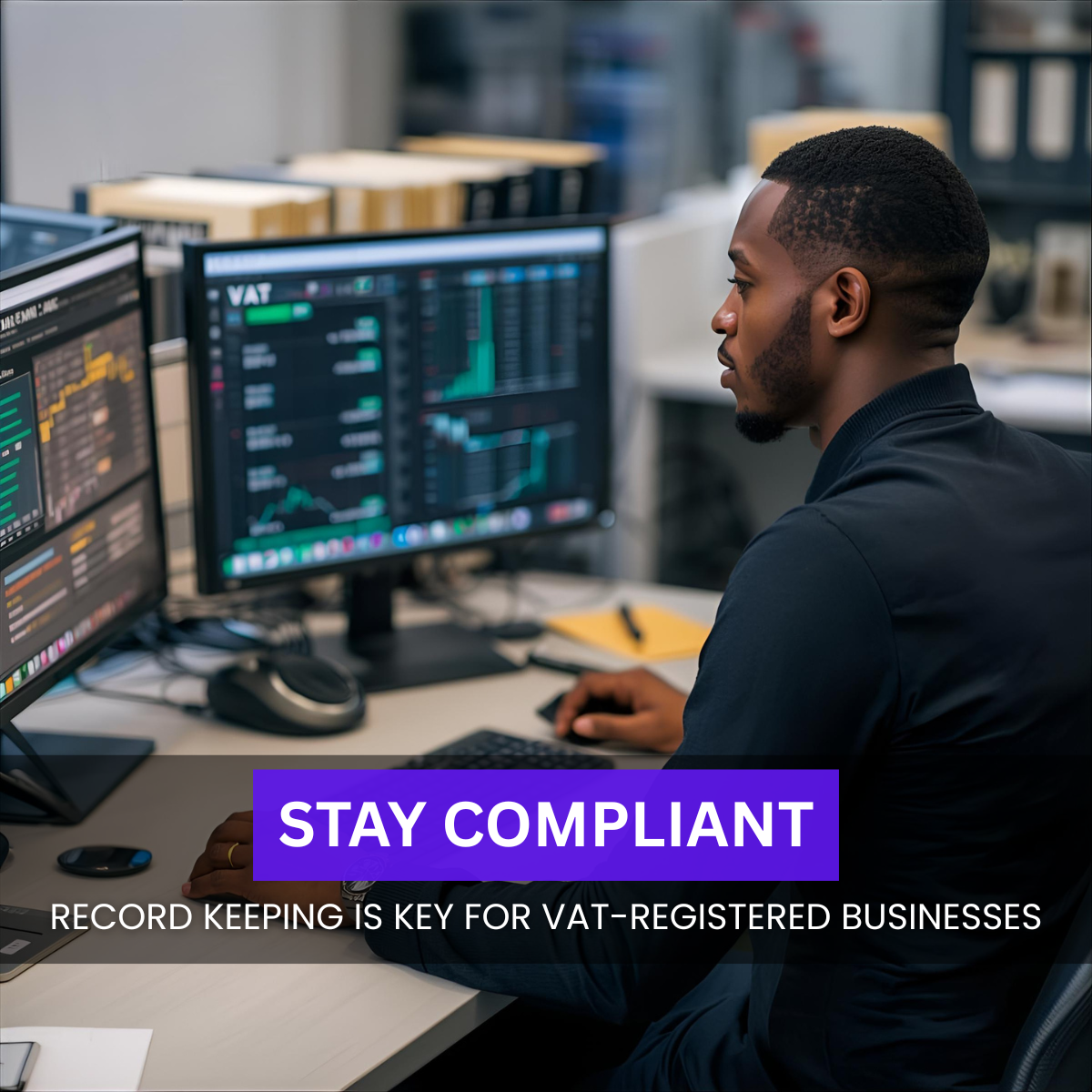Black British accountant in a UK office reviewing VAT spreadsheets on dual monitors.
